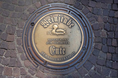 Municipal manhole cover with an advert for a wine bar, Biberach an der Riß, Baden-Württemberg,