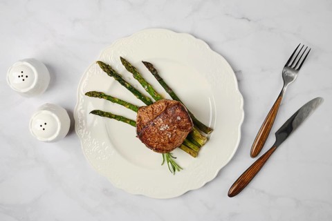 Savor a perfectly cooked filet mignon paired with tender asparagus stalks on a decorative white