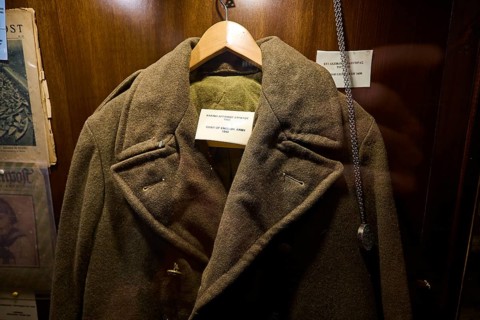Old British military coat on a hanger in an illuminated wooden display case, War Museum, Military