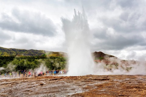Active Strokkur, tourists observe eruption, high temperature area Haukadalur, tourist attraction at