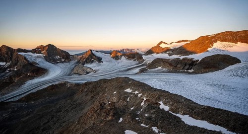 Picturesque high mountain landscape at sunrise with alpenglow, glacier and rocky mountain peaks in