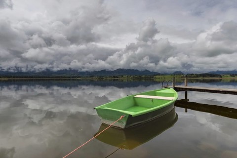 Storm clouds at sunset, a green rowing boat lashed to the wooden jetty, Hopfensee, Hopfen am See,