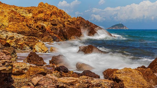Rugged rocks and foaming spray on Topinetti beach, near Rio Marina, Elba Island, Tuscan Archipelago
