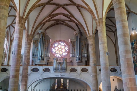 Church interior with organ, rose window and Gothic vaults, Merano, Italy