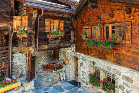 Old wooden houses in log construction, decorated with flowers, historic village centre, Grimentz,