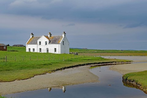 Lonely white house in a green field under a cloudy sky, Isle of Harris, Hebrides, Scotland, United