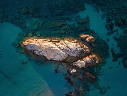 A rock formation rises out of the turquoise-blue water on the Costa Rei, a stretch of coastline on