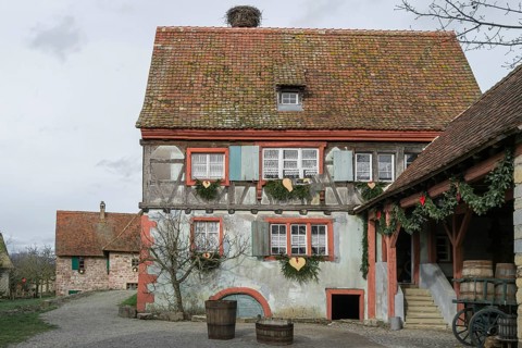 Half-timbered house with colourful paintwork, wooden shutters and rustic charm, surrounded by rural