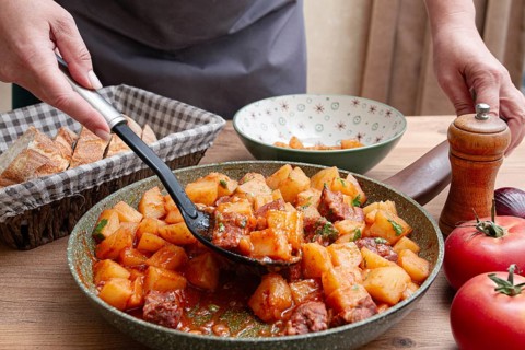 Homemade stew with potatoes and meat, cooked in a frying pan, is served on a plate
