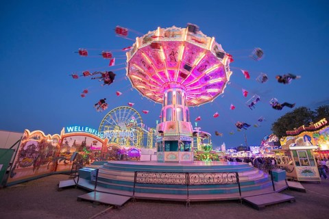 Brightly illuminated carousel turns at a night fair, chain carousel, spring festival, Cannstatter