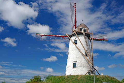White painted windmill with red wings in front of a blue sky, Bruges, Belgium