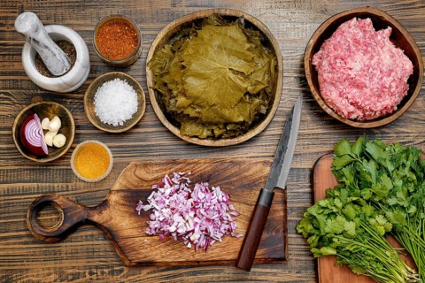 Fresh ingredients are prepared for making dolma at home. Minced meat, spices, vine leaves are laid
