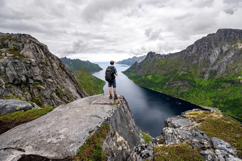 View of Øyfjorden fjord and mountains, view from Barden mountain, young man standing on a cliff,