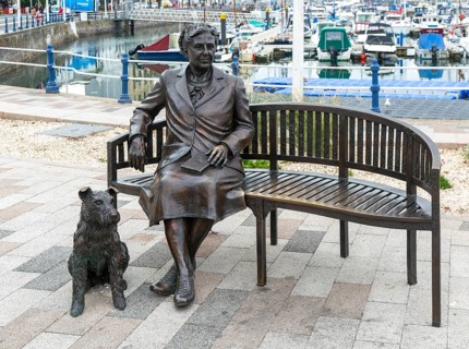Bronze sculpture statue artwork Agatha Christie sitting on bench with her dog, Torquay, Devon,