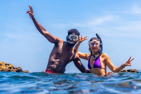 Young multi ethnic couple wearing snorkeling masks and enjoying summer vacation in tropical sea
