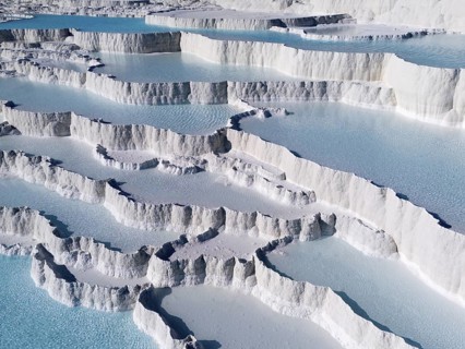 White limestone terraces with turquoise-coloured water under a clear sky, aerial view, sinter