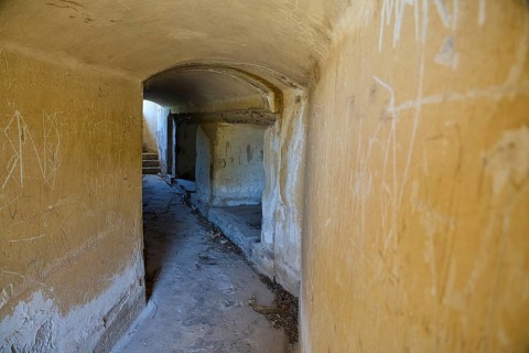 Long corridor with weathered walls leading into the darkness, mysterious and abandoned, Italian