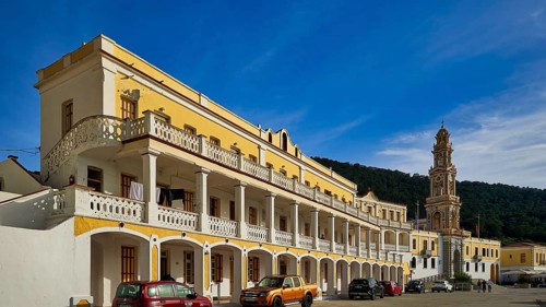 Yellow building with balconies, vehicles in front, blue sky in the background, Holy Week, Bay of