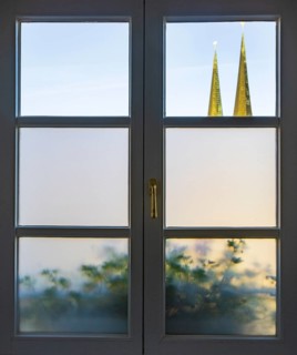 View through a closed window to the collegiate parish church of St Philip and St James, place of