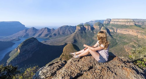 Hiker enjoying sunset at Blyde River Canyon with Three Rondawels peak, view of canyon with Blyde