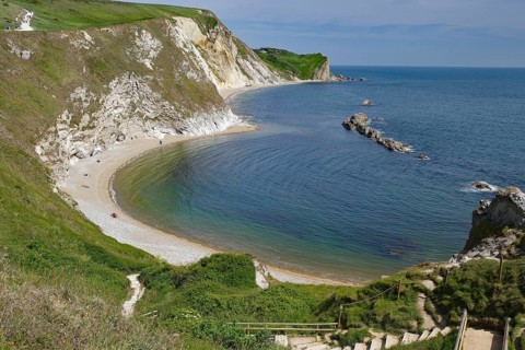 Curved coastline with sandy beach and cliffs, calm sea, Durdle Door, Weymouth, Dorset, England,
