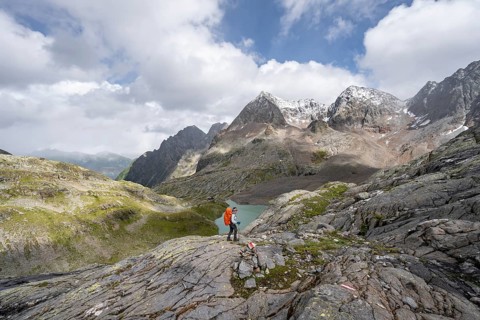 Mountaineer on a rocky hiking trail, view of the turquoise-blue mountain lake Großer Gradensee,