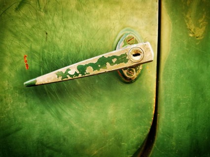 A close-up view highlights a vintage green metal latch on a door, showcasing its worn texture and