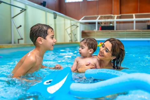 Mother and children enjoying time together, playing with inflatable toys in a swimming pool,