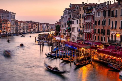 View of the Grand Canal with gondoliers at sunset, picturesque evening mood with illuminated