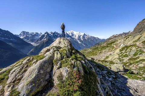 Mountaineer on a rock, mountain panorama with glaciated mountain peaks, Aiguille du Midi and Mont
