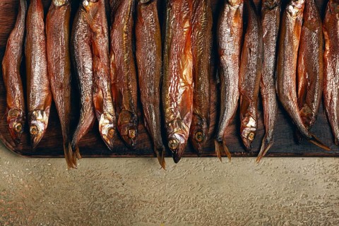 Cold smoked capelin, on a wooden chopping board, no people