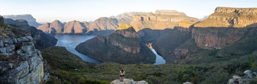 Hiker enjoying panorama, sunset at Blyde River Canyon with Three Rondawels peak, view of canyon
