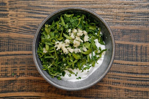 Freshly chopped herbs, including parsley and garlic, are mixed with creamy yogurt in a rustic