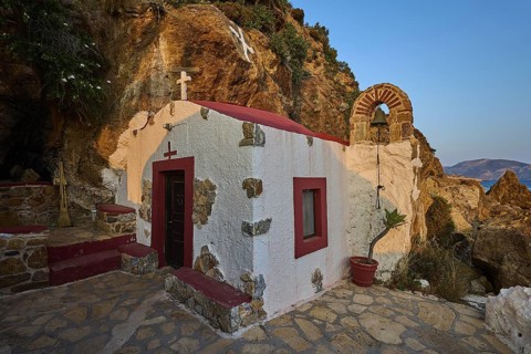 Legend, crab, shell fisherman, rock embedded chapel with cross and bell arch, surrounded by coastal