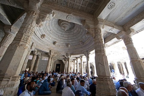 Indian men praying between the white marble pillars in the Adinath temple in Ranakpur, Jain temple,