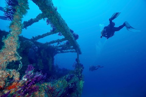 Divers explore a shipwreck in deep, clear water. Dive site wreck Le Grecq, Giens peninsula,