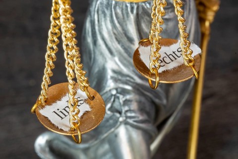 Symbolic image: Close-up of the scales of Justitia with two torn-off leaves labelled LEFT and RIGHT