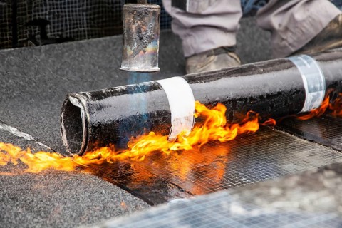 Roofers during waterproofing work with bitumen membranes