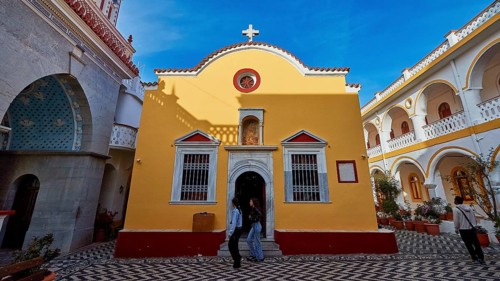 Yellow baroque-style church with cross and floor pattern in the courtyard, Holy Week, Panormitis