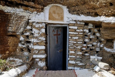 A rustic stone door with a cross symbolises a cave entrance that carries religious significance,