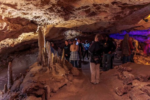 Tourists walking past limestone rock formations in a cave at Florida Caverns State Park in the