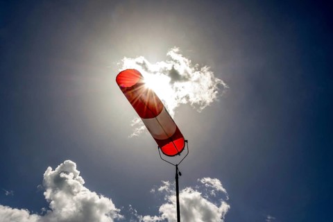 A colorful windsock hangs from a tall pole, clearly indicating wind direction. The bright sky is