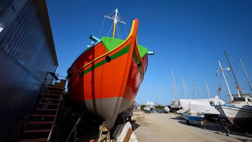 Frontal view of a ship's bow in orange and green on a shipyard site, Diakofti boatyard, new