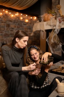 Two friends are seated together in a warm and inviting room, engaging in a joyful moment as one