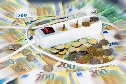 Symbolic image of electricity costs: multiple socket outlet with euro banknotes and euro coins