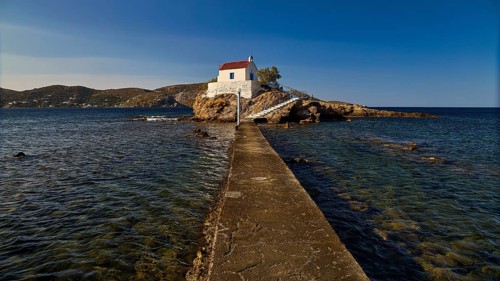 White chapel with red roof on a small island, connected to the mainland by a footbridge, chapel,