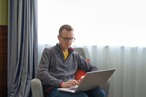 A middle-aged man sits comfortably in an armchair and watching as real estate agent showing a