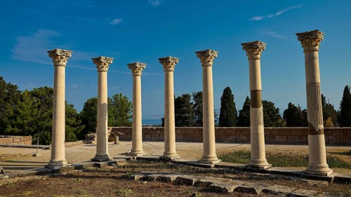 Six ancient columns with capitals in front of a clear sky, part of a historical site, Temple of