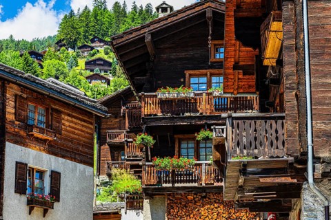 Old wooden houses in log construction, decorated with flowers, historic village centre, Grimentz,