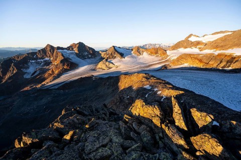 Picturesque high mountain landscape at sunrise with alpenglow, glacier and rocky mountain peaks in